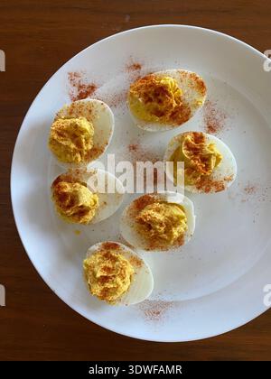 Deviled eggs sprinkled with paprika on a white plate, classic homemade appetizer for Easter and spring gatherings. Stock Photo