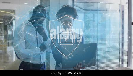 Studying two professionals in suits reviewing laptop in corporate office, with security overlay Stock Photo