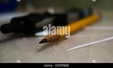Macro shot of a sharp graphite pencil on a workspace table with a blurred background. Professional drawing tools, architectural sketching Stock Photo