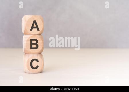 Directly above view of three wooden blocks with letters A, B, C stacked vertically on a light neutral desk. Minimalist concept with copy space. Stock Photo
