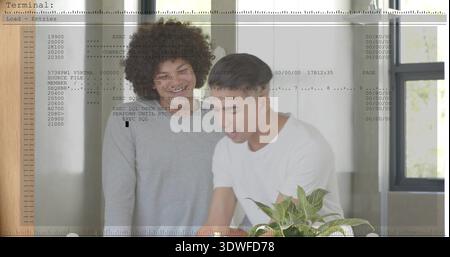 Leaning two men studying code on table at home office, wearing shirts with terminal overlay Stock Photo