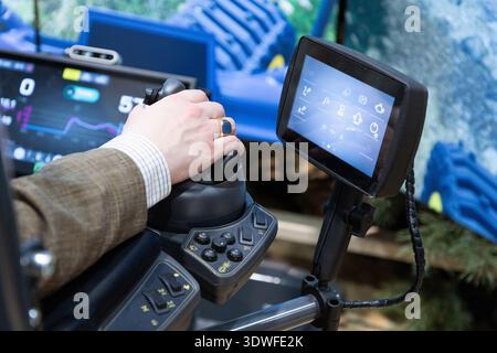 Berlin, Germany - January 22, 2024: Operator is using advanced machinery control panel with digital display and ergonomic joystick. Stock Photo