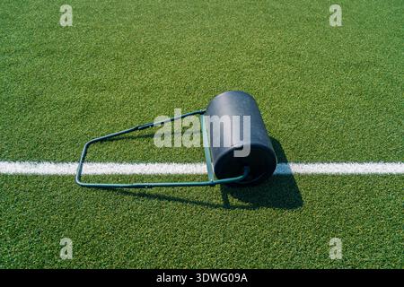 A freshly renovated soccer field featuring a turf roller placed on the lush green grass, showcasing the maintenance process. The white line highlights Stock Photo