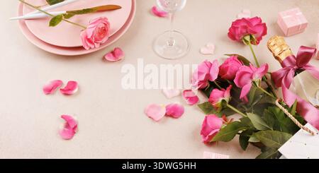 Romantic table setting with pink roses, champagne, and petals Stock Photo