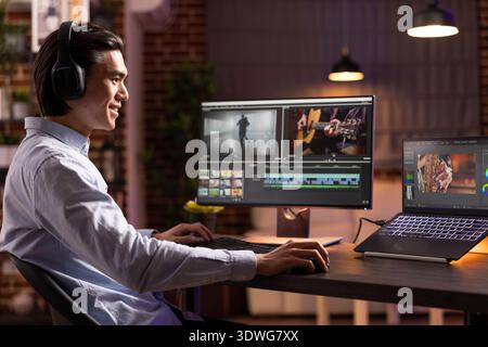 Focused man wearing headphones edits cinematic video and audio content on computer. Male filmmaker works from home, enjoying post production and storytelling through sound and visuals. Stock Photo