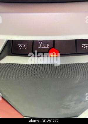 Control panel in a bus showing illuminated warning lights for seatbelt and refreshment service indicators, with a textured surface and buttons visible Stock Photo