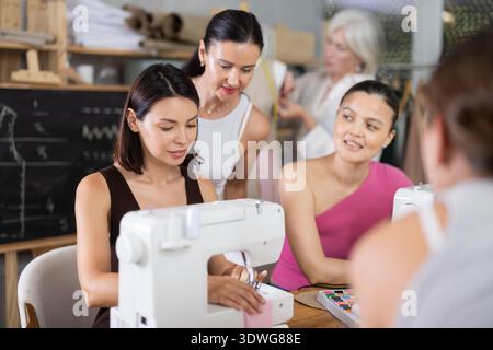 Young woman working at machine during group sewing course Stock Photo
