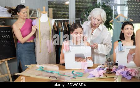 Sewing teacher guiding student during machine work Stock Photo
