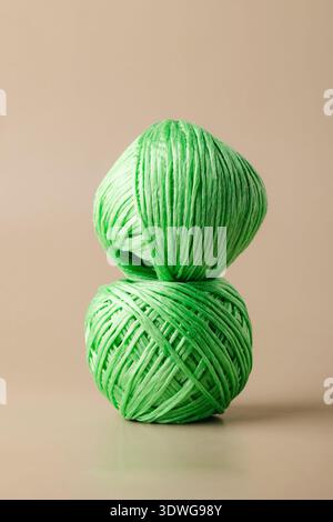 A ball of green recycled polyester synthetic fabric on beige background. Green living, plastic recycling, reuse Stock Photo