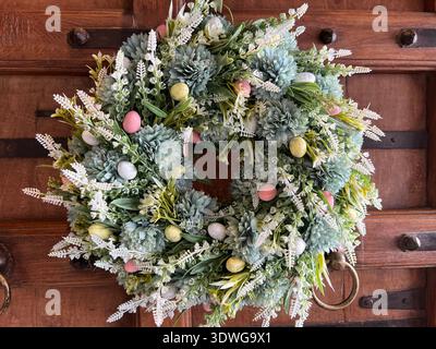 Spring floral wreath with decorative Easter eggs on a wooden door Stock Photo