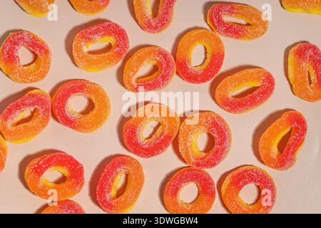 A collection of vibrant orange and red peach ring candies coated with sugar, arranged on a light background. Stock Photo