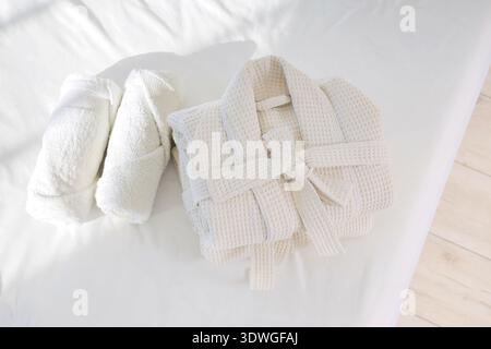 Folded bathrobes with towels on bed in hotel room, top view Stock Photo