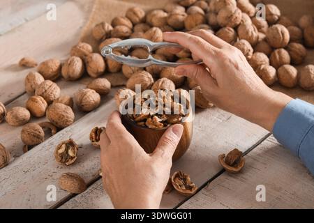 Female hands with walnuts and nutcracker at wooden table Stock Photo