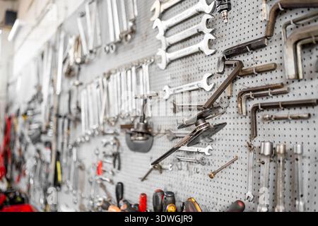 Various hand tools neatly arranged on perforated wall inside workshop. Organized work environment and industrial maintenance concept Stock Photo