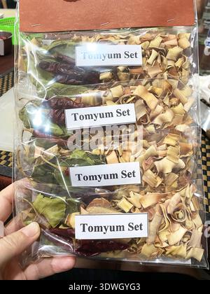Dried Tom Yum spice set is held in a hand, showcasing different herbs and spices in clear packaging, with labels visible for culinary applications Stock Photo