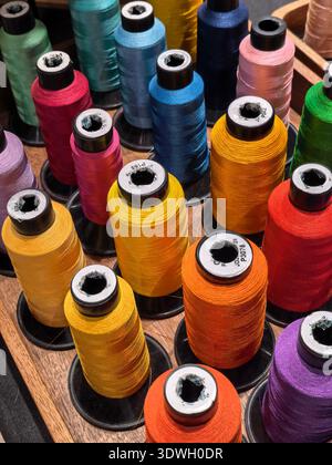 Vibrant spools of sewing thread arranged in a colorful display for crafting and tailoring Stock Photo