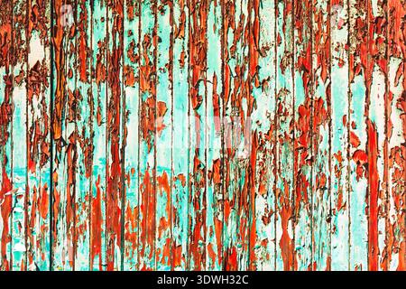 Weathered surface with peeling turquoise and rust colored paint, revealing layers of texture and decay. The mix of colors creates an abstract Stock Photo