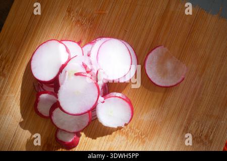 Sliced radishes on a wooden cutting board in sunlight Stock Photo