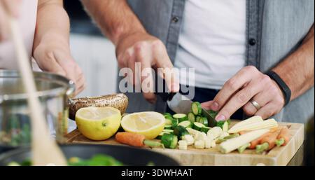 Vegetables, cutting and hands of couple in kitchen for nutrition, bonding and healthy cooking. Food, support and marriage with man and woman helping Stock Photo