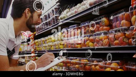 Checking white polo dark apron clerk noting clamshells on grocery shelf, clipboard, HUD, copy space Stock Photo