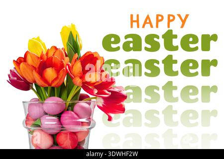 Happy Easter celebration with colorful flowers and eggs in a glass vase on the table Stock Photo