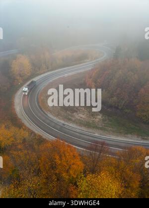 Aerial view of a winding road through the autumn forest and green ...