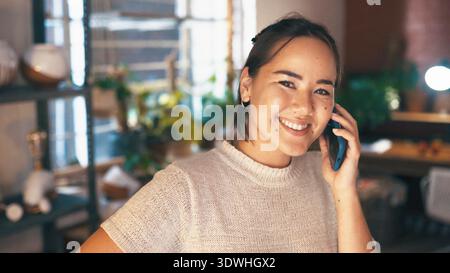 Phone call, portrait or woman in shop with pottery, client chat or negotiation with clay supplier. Happy, networking or Asian owner with tech Stock Photo