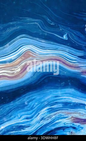 Abstract acrylic fluid art painting creating dynamic swirling patterns and waves of blue, white, and subtle brown colors, offering a textured surface Stock Photo