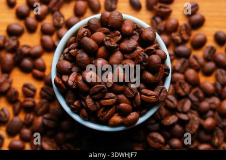 Coffee beans in a bowl on wooden background. Top view stock image Stock Photo