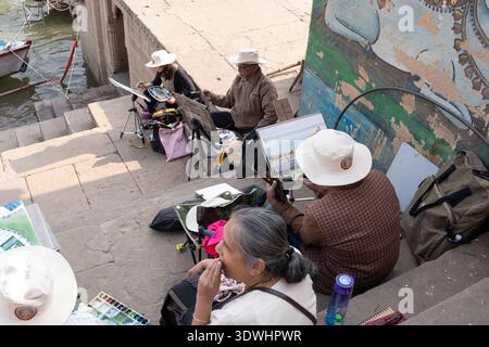 Artists painting outdoors at an Indian painters' workshop on river steps in Varanasi, India. Stock Photo