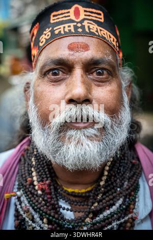 Portrait of a Sadhu monk wearing traditional beads and headband at a funeral crematorium in Varanasi, India. Stock Photo