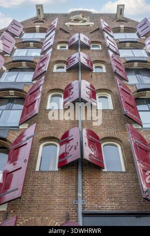 Netherlands. A day in Amsterdam. Bottom view of an old brick house with open red shutters on the windows Stock Photo