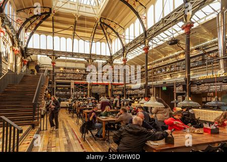 Mackie Mayor food hall interior, Manchester — busy diners beneath a magnificent restored Victorian market hall roof. Stock Photo