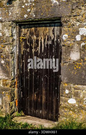 Weathered wooden door is set into the thick stone wall of a traditional Yorkshire Dales barn Stock Photo