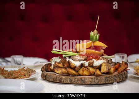 Baked potatoes with vegetables and fruits on a wooden stand, in restaurant Stock Photo
