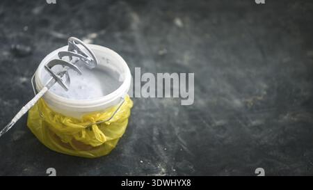 Drill paddle mixer on a bucket with white paint, DIY tools and accessory, banner with copy space Stock Photo