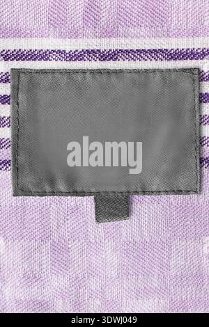 Blank black patch label stitched on lavender color cotton fabric background Stock Photo