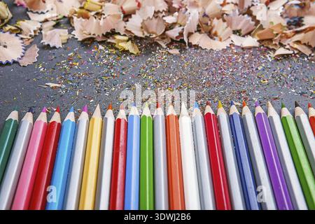 Close up shot of colored pencil crayons and pencil crayons shavings on dark background. Sharpened colored pencils Stock Photo