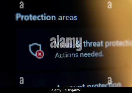 Close-up of virus and threat protection settings on a computer screen showing a red alert icon and actions needed message, cybersecurity risk and syst Stock Photo