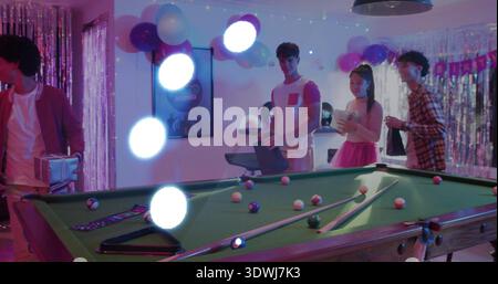 Dominating pool table sitting in rec room, with cues, birthday banner, guests in casual clothes Stock Photo
