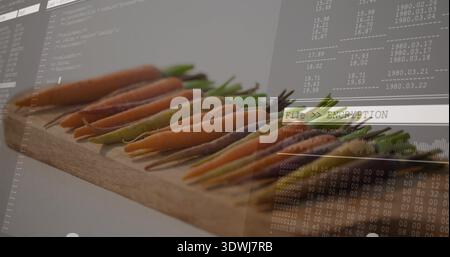 Displaying row of baby carrots with green tops on wooden board, showing File  ENCRYPTION overlay Stock Photo