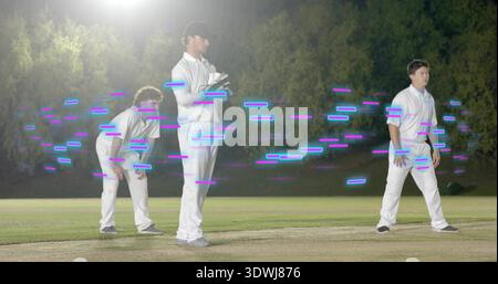 Posing three men in white on night pitch wearing gloves, floodlit, magenta or cyan light Stock Photo