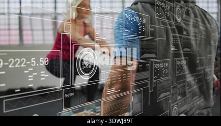 Reaching man in hoodie touching translucent glass partition at modern lab, revealing data panels Stock Photo