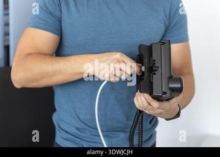 VoIP Telephony, technical support, services. Specialist connects the phone to the network Stock Photo