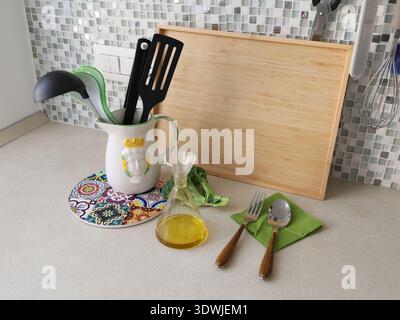 Kitchen utensils in jug and on kitchen counter. High-quality homemade olive oil from farmer. Healthy eating. Traditional Italian kitchen and interior Stock Photo