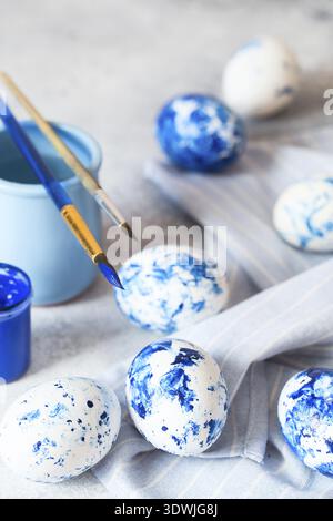Dyed Easter eggs. Ð¡lassic blue 2020 Easter eggs on the grey background. Blue speckled easter eggs with paint and brushes. Decorating eggs, preparing Stock Photo