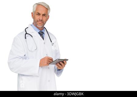 Mature male doctor wearing lab coat and stethoscope, using tablet and stylus in studio, copy space. Portrait, physician, professional, white, device, Stock Photo