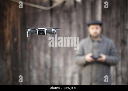 Old fashioned men from village mastering to fly drone, basics of remote control Stock Photo