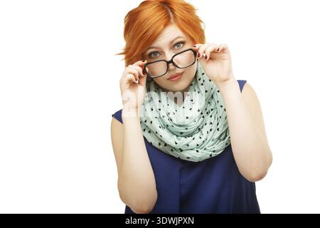 Portrait of surprised red-haired young woman holding glasses on her nose isolated on white background Stock Photo