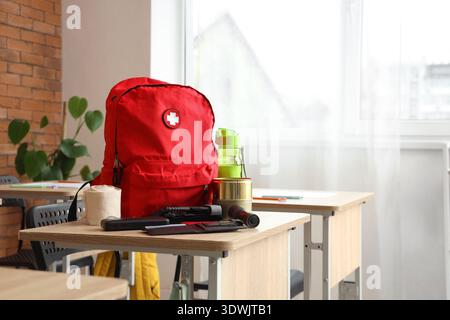 Emergency backpack with necessities on desk in classroom Stock Photo